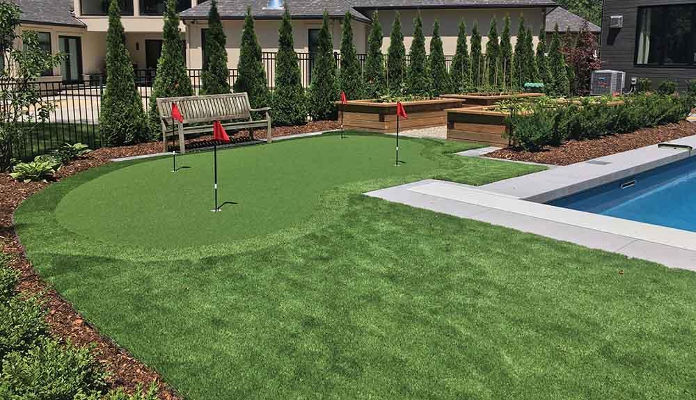 A backyard with a putting green and a pool.