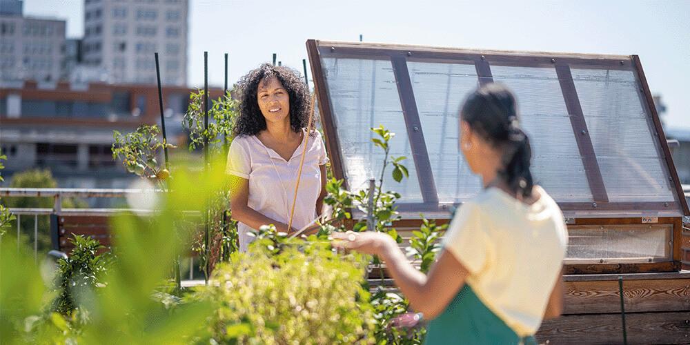 Two women standing next to a solar panel on a rooftop.