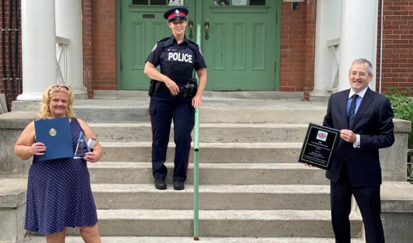 Three people standing on the steps of a building with a police officer.