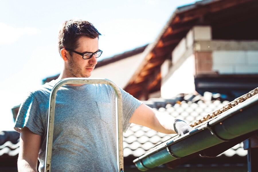 A man holding a ladder on top of a roof.