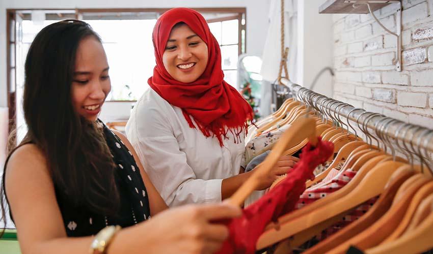 Two women looking at clothes on a rack.