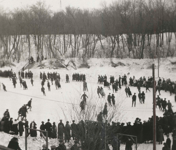 Groups of people gathered on a snowy landscape, many standing on a frozen body of water.