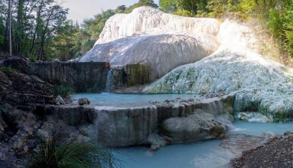 A waterfall in the middle of a wooded area.