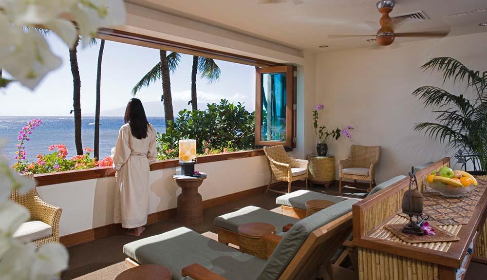 A woman is sitting in a room overlooking the ocean.