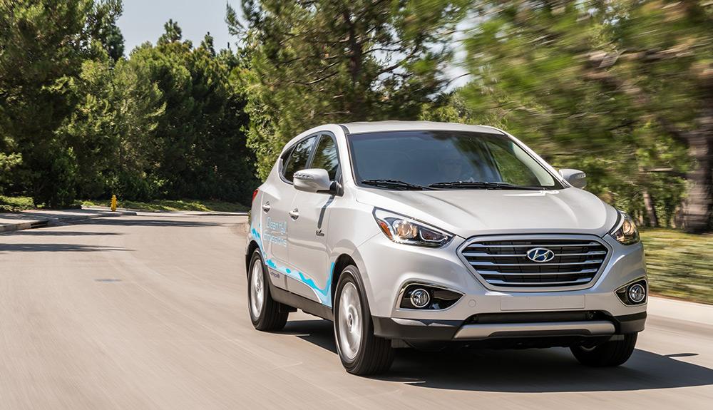 Silver compact suv driving on a road flanked by greenery.