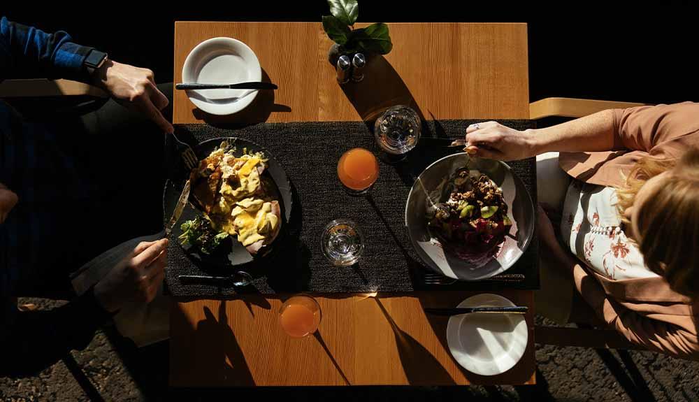 Two people sitting at a table eating food.