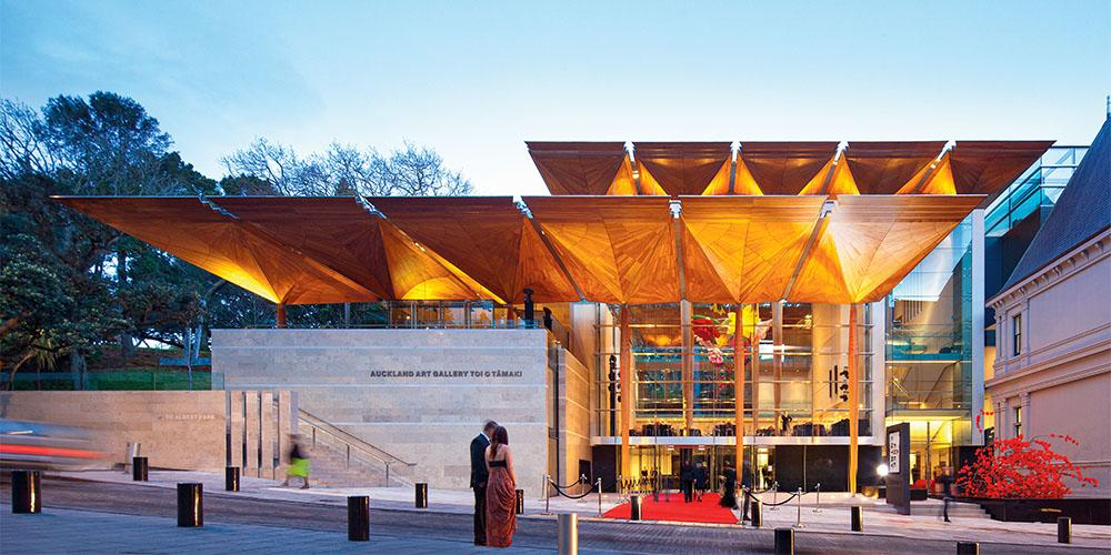 Modern building entrance with distinctive angular canopy illuminated at twilight.