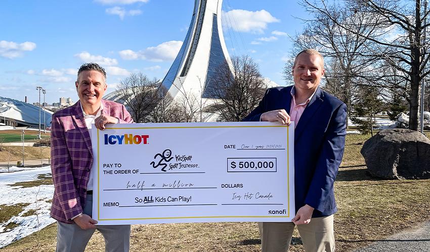 Two men holding a check in front of the olympic tower.