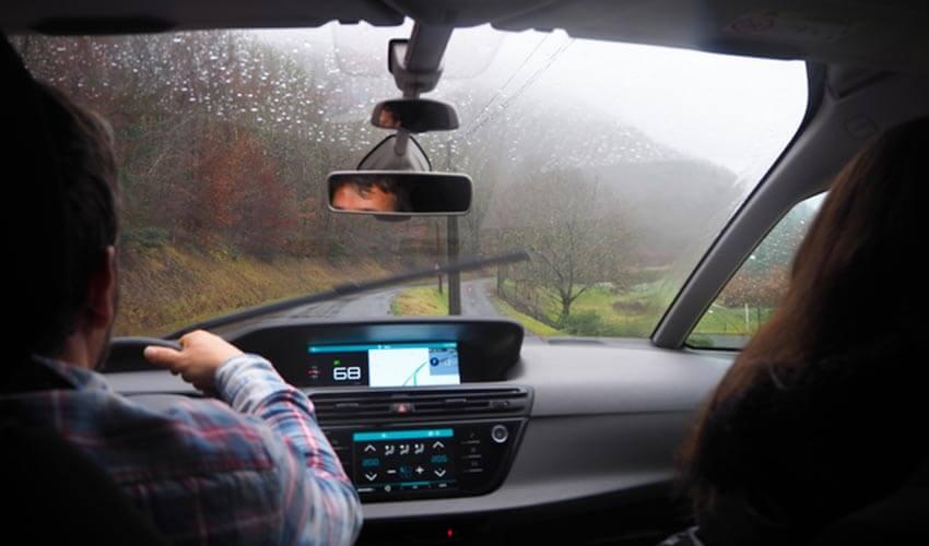 A man and woman driving a car on a rainy day.