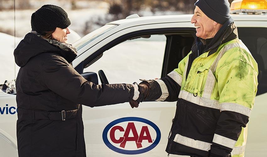 A man and woman shaking hands in front of a white truck.
