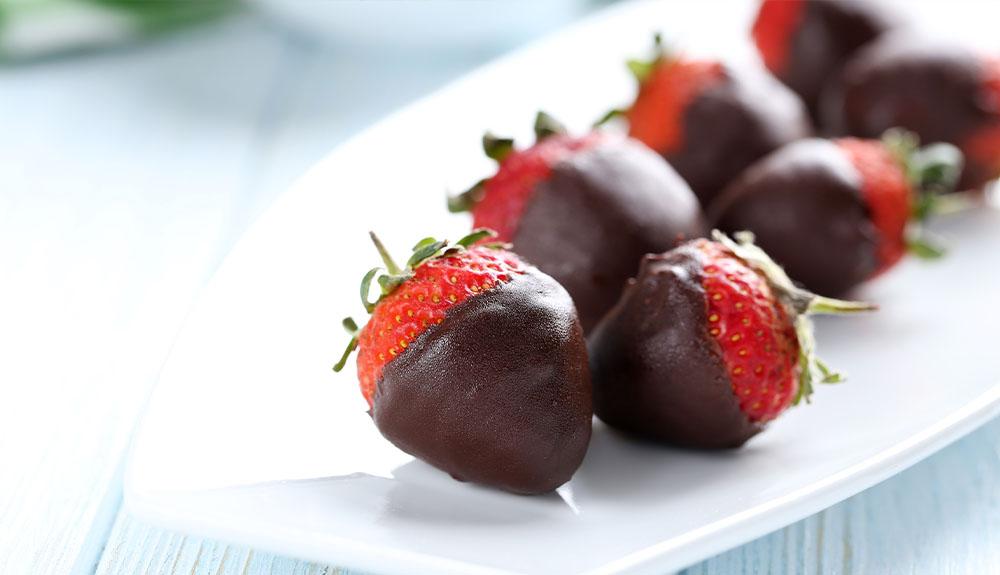 Chocolate covered strawberries on a white plate.