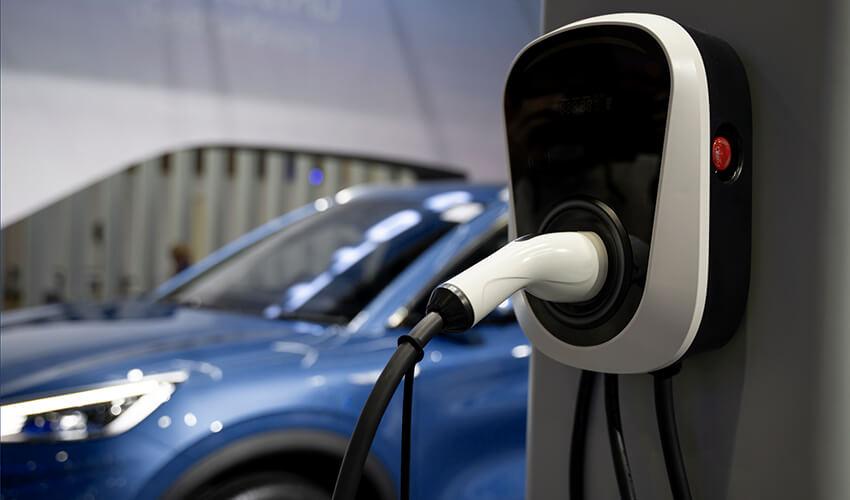 A blue car is plugged into an electric charging station.