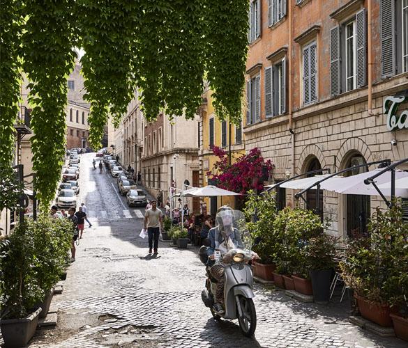 A person riding a moped down a cobblestone street.