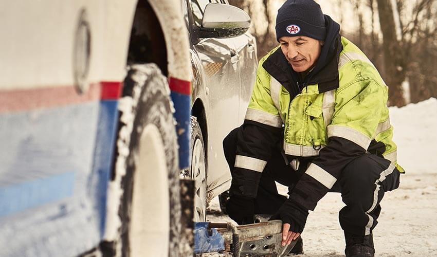 A man working on a car in the snow.