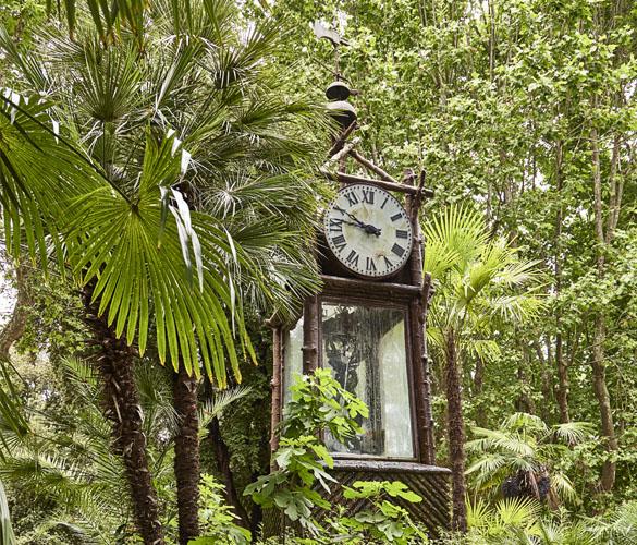 A clock tower in the middle of a forest.