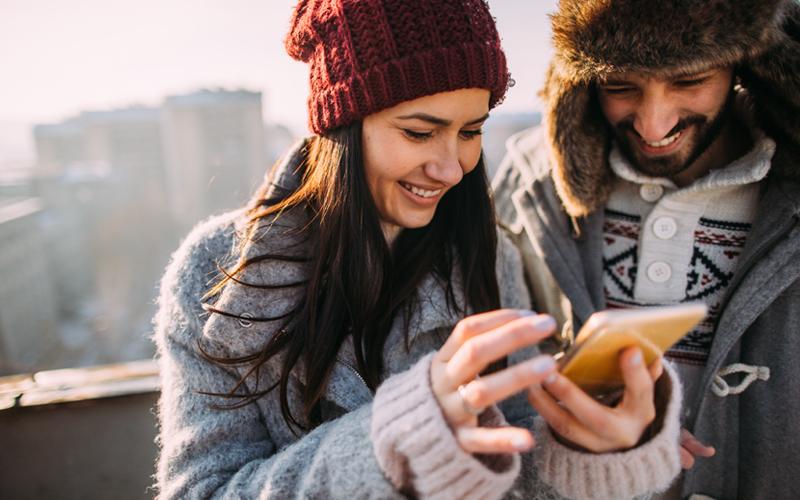 Two people outside looking at a phone together.