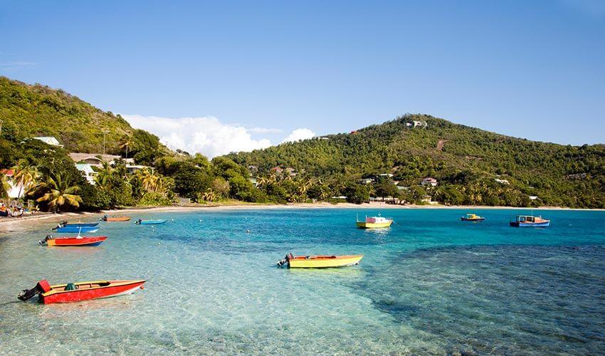Colorful boats are docked on a beach near a hill.