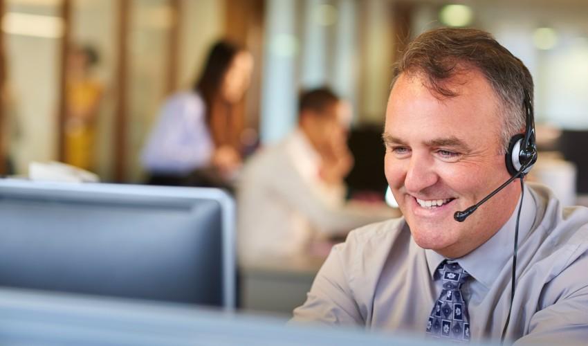 A man wearing a headset in front of a computer.