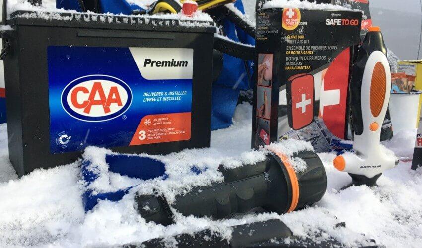 A snow covered car with a battery and other items.