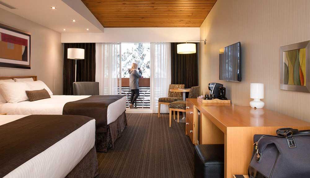 A hotel room with two beds and a television.