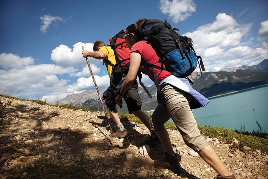 Two people hiking up a hill with backpacks.