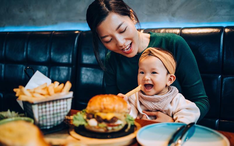 Mother and a baby at a restaurant sitting in a booth.