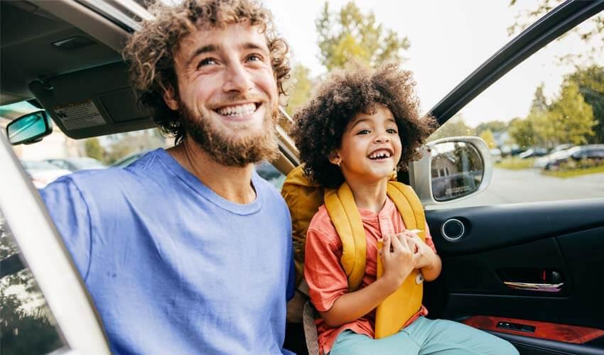 A man and a child sitting in the back seat of a car.