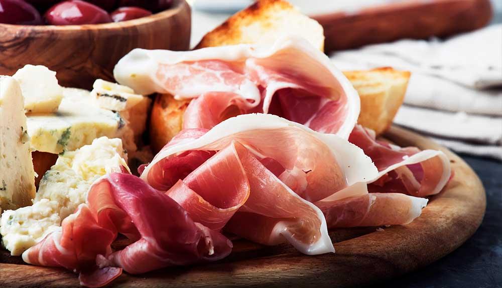 A plate of cheese, olives, and bread on a table.