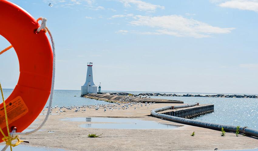 A life preserver on a pier with a lighthouse in the background.