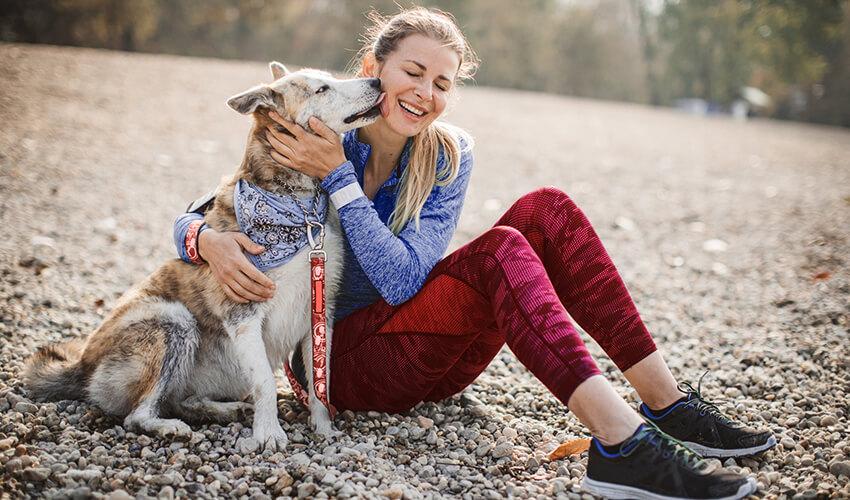 A woman is hugging her dog in a park.