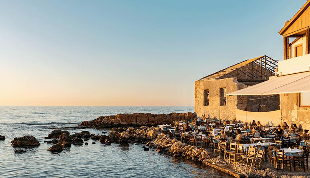 A restaurant by the water with tables and chairs.
