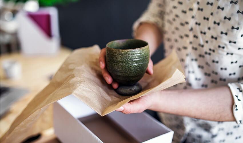 A person holding a cup out of a box.