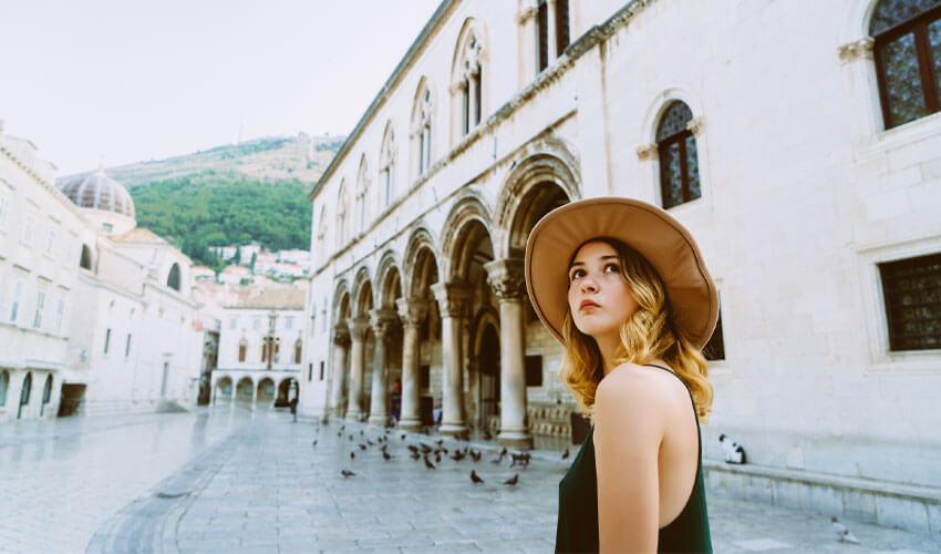 A woman wearing a hat in front of a building.