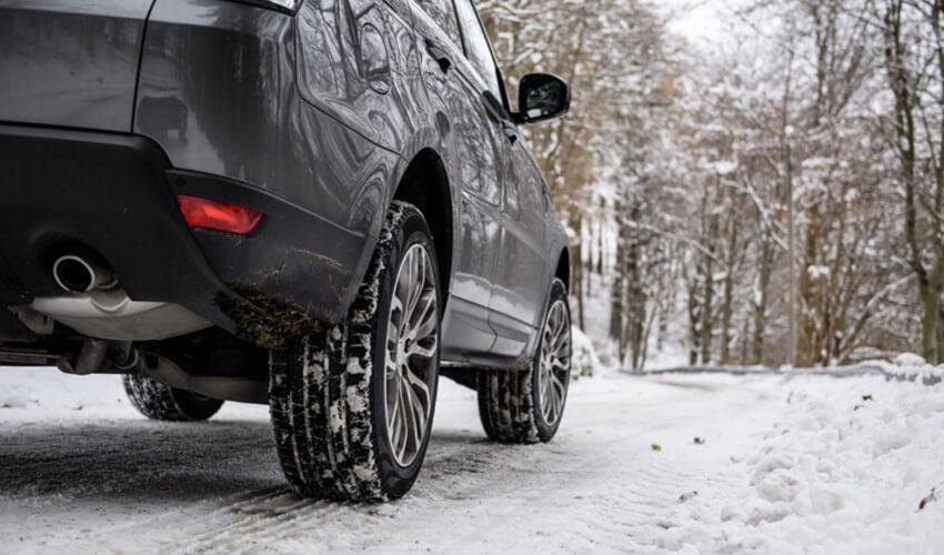A black suv driving down a snowy road.