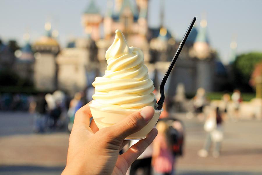 A person holding an ice cream in front of a castle.