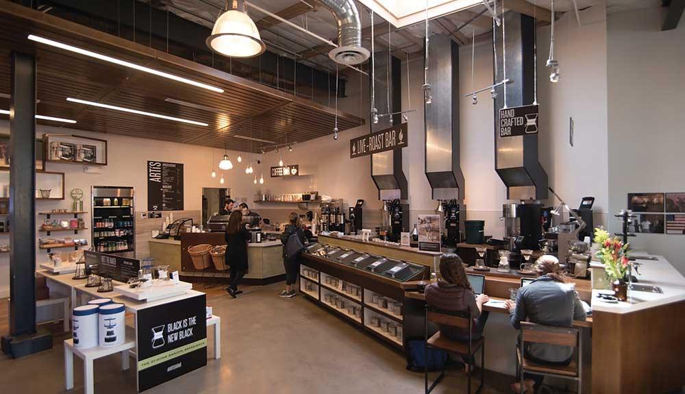 The interior of a coffee shop with people at the counter.
