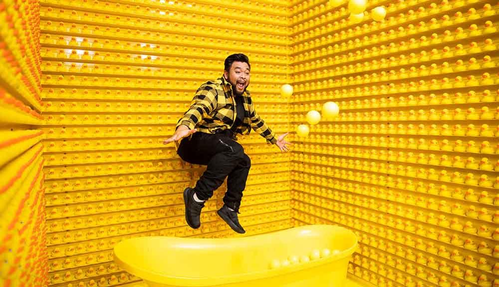 A man jumping in a yellow bath tub.