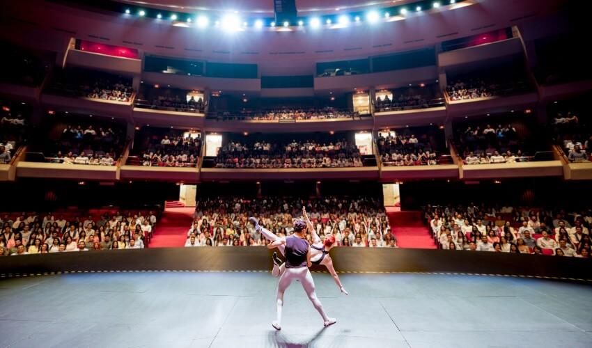 Two dancers on stage in a large auditorium.