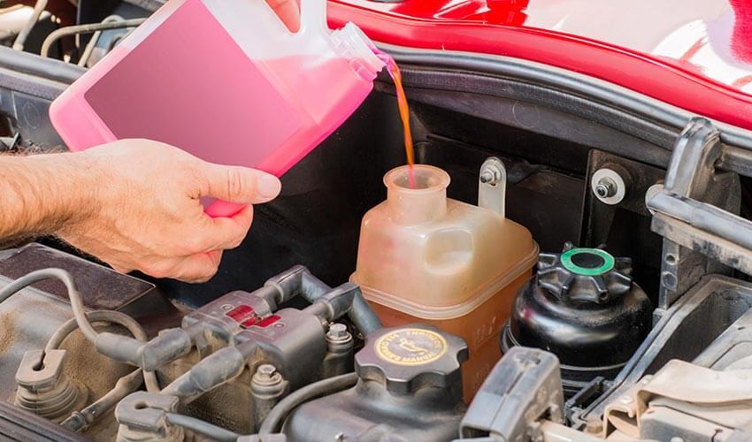 A man pouring oil into the engine of a car.