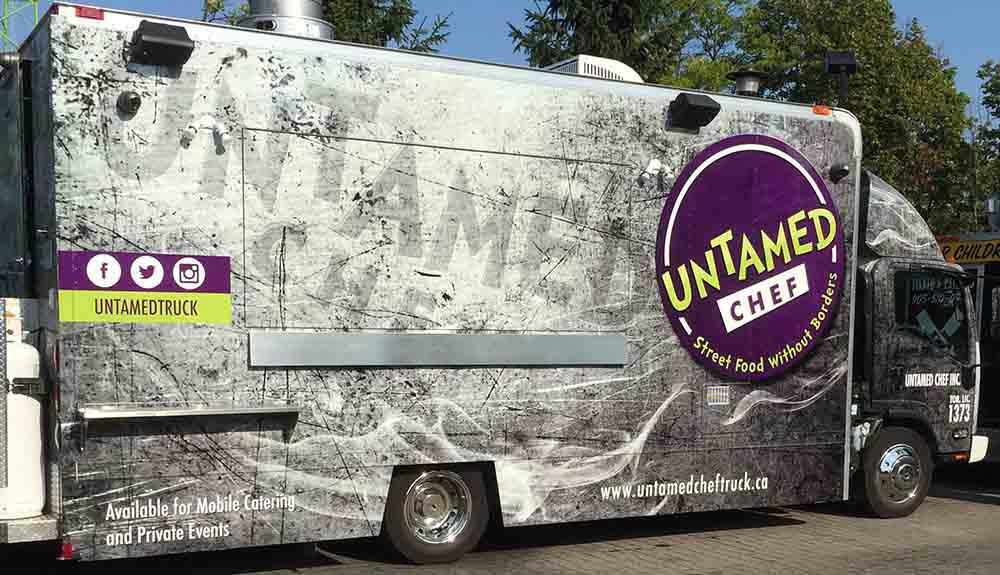 A food truck is parked on the side of the road.