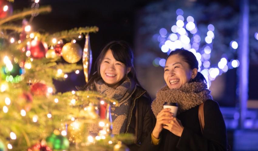 Two women standing next to a christmas tree.