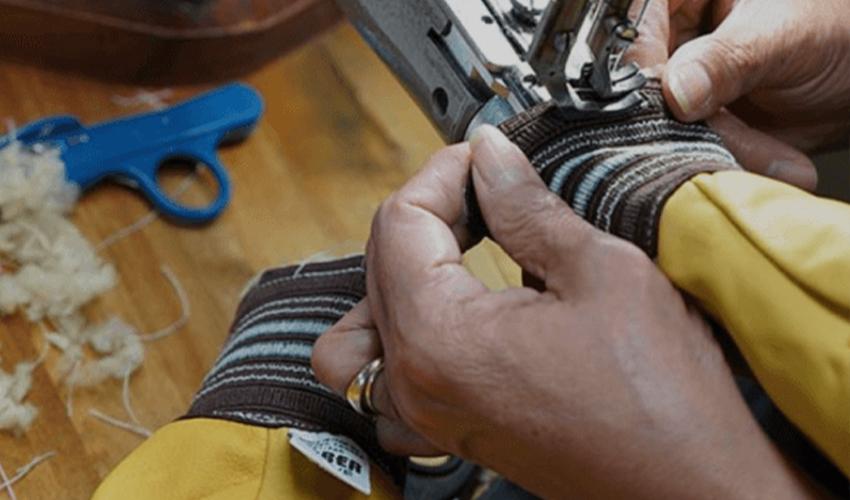 A person using a sewing machine on a wooden table.