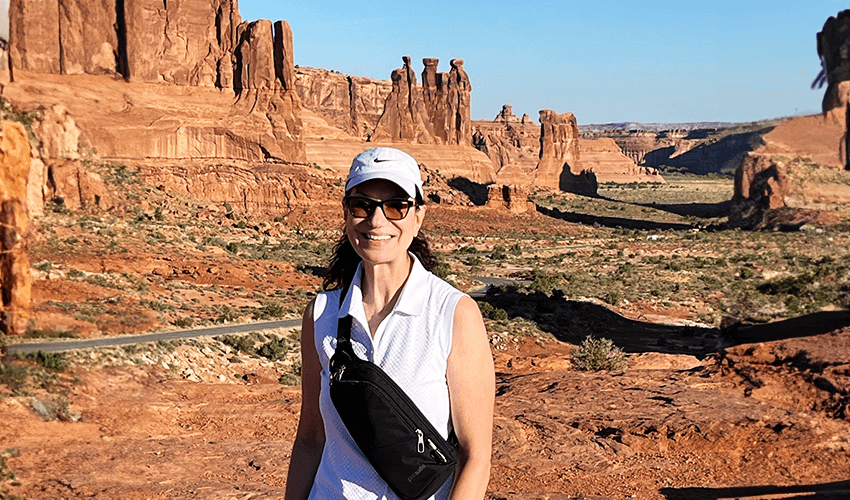 A woman standing in front of a red rock formation.