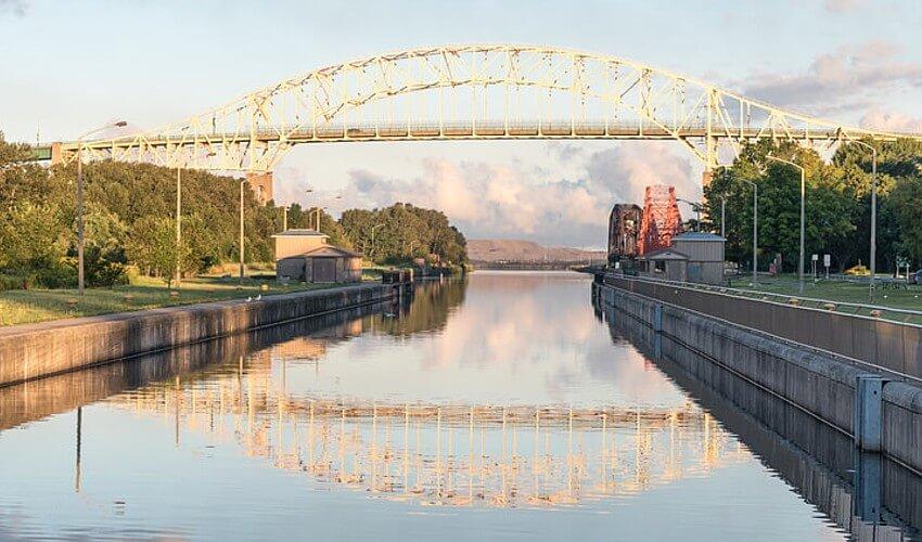 A bridge over a canal with a boat in the background.