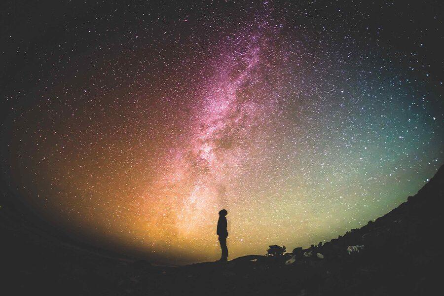 A person standing under the milky in the night sky.