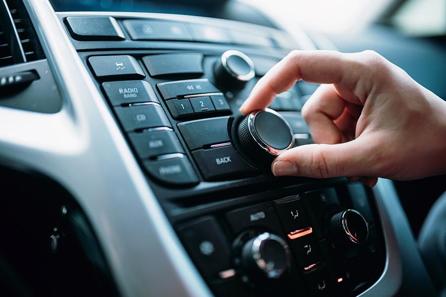 Adjusting the car stereo volume control knob.