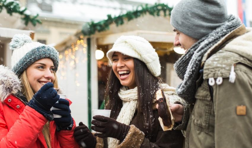 A group of people drinking coffee in a winter market.