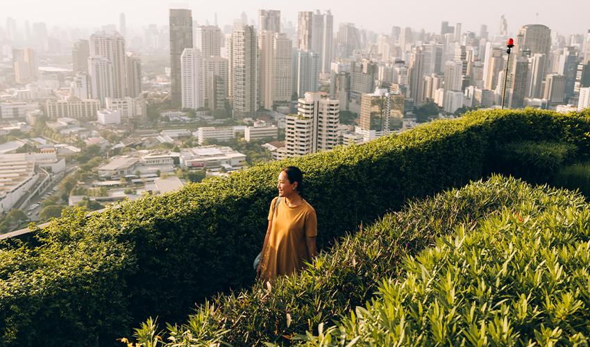 A woman in a yellow dress standing on a balcony overlooking a city.