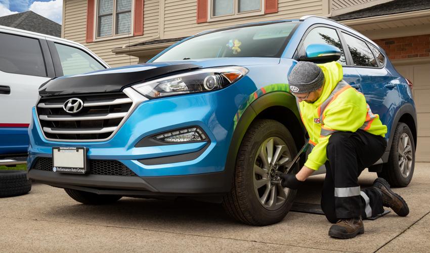 A man fixing a tire on a blue suv.