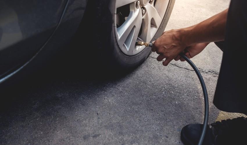 A man is using a hose to change the tire on a car.
